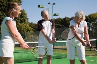 Adults practising on an outdoor tennis court
